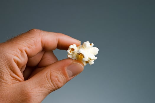 A hand holding a piece of popcorn photo