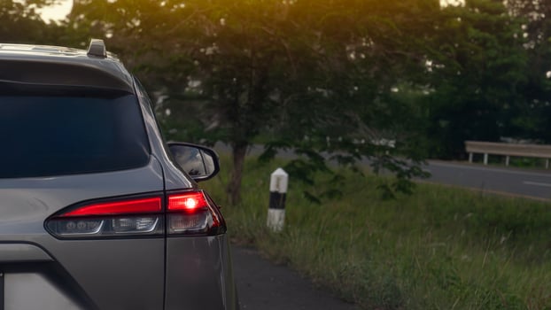 Luxury of grey car open light brake on the asphalt road. side road with trees and grass. On the opposite side is an empty road. photo
