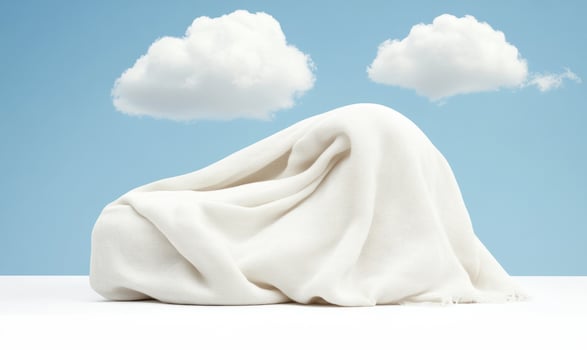 Soft White Blanket Draped Over Object with Blue Sky and Fluffy Clouds in a Minimalist Style Emphasizing Calm and Tranquility in Indoor Space photo