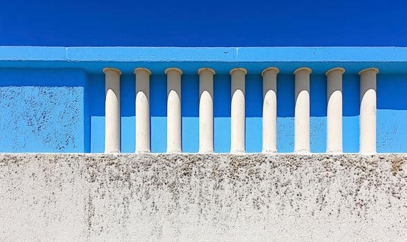 Abstract architectural design featuring elegant white columns against a vibrant blue wall under a clear blue sky showcasing minimalist beauty and simplicity photo
