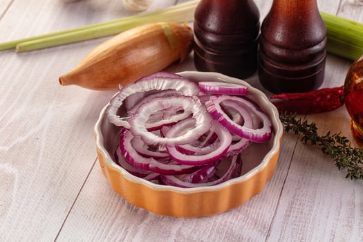 A bowl of onions and other ingredients on a wooden table photo