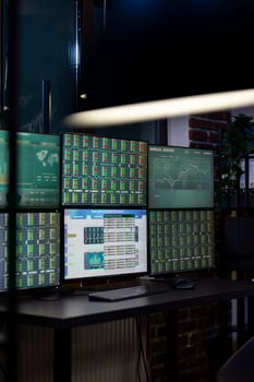 Vacant workstation with multiple monitors displaying forex charts, arranged in a modern office for traders. Computer screens showing financial data, ready for night shift employees. photo