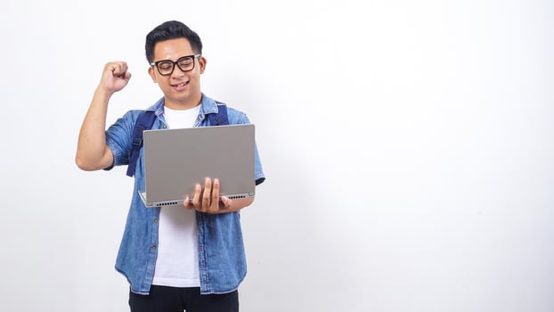 Young Asian male university student in casual outfit with backpack and holding open laptop isolated on white background photo