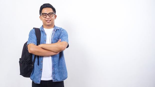 Handsome young Asian male university student in casual outfit with backpack crossing his arms in front of his chest isolated on white background photo