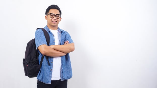 Young Asian male university student in casual outfit with backpack crossing his arms in front of his chest isolated on white background photo