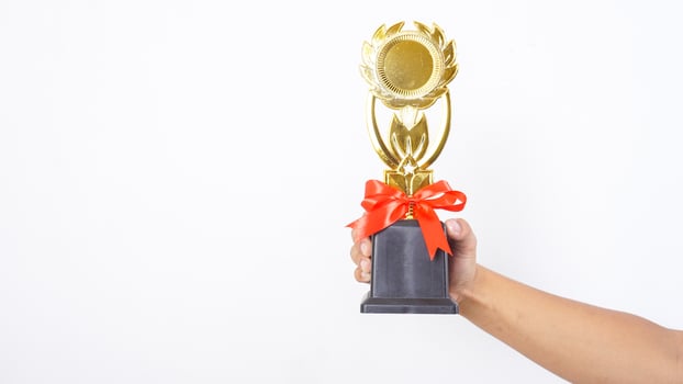 Close up of hand holding trophy isolated on white background photo