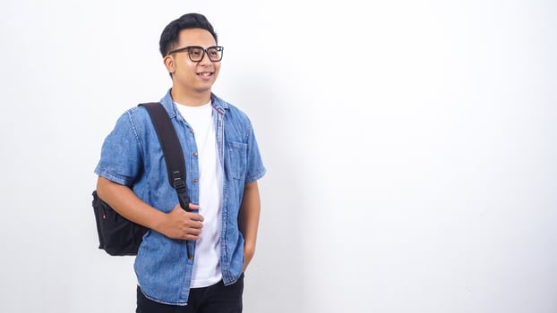Young Asian male university student in casual outfit with backpack isolated on white background with copy space photo