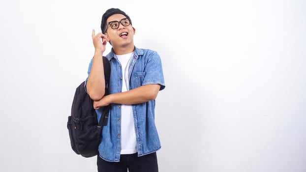 Portrait of smiling young Asian male university student in casual outfit with backpack isolated on white background photo