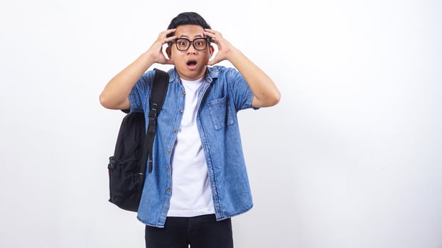 Frustrated young Asian male university student in casual outfit with backpack isolated on white background photo