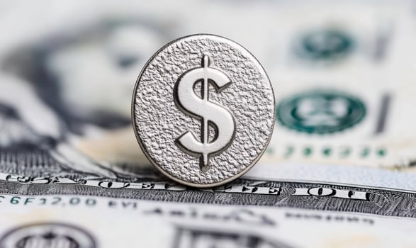 Silver dollar symbol on textured surface overlaid on US banknotes with blurred background highlighting concepts of finance, wealth, and currency transactions photo