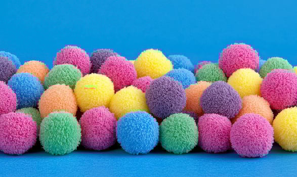 Colorful Craft Pom Poms in Various Shades Spread Across a Blue Background for Creative Arts and Child-Friendly Projects and Activities photo