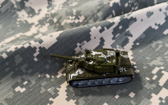 Camouflage toy tank on military background photo