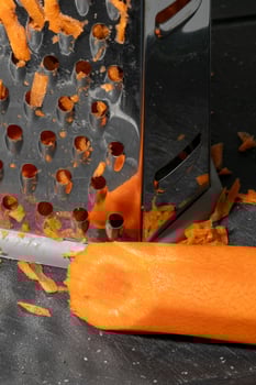 Grated carrots with a metal grater, perfect for healthy cooking concepts and Easter preparation, vibrant kitchen close up photo