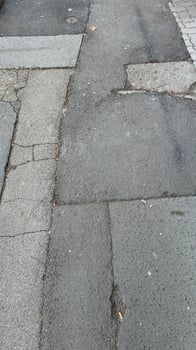 Cracked urban sidewalk with weathered texture symbolizing urban decay, infrastructure challenges, and city life realities photo