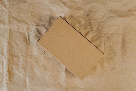 Cardboard box on crumpled craft paper. Flat lay. Delivery concept photo