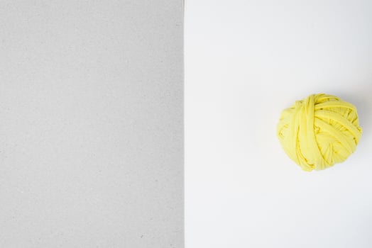 Yellow rag ball and gray cardboard. Trending colors of 2021. Flat lay, copy space photo