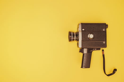 Classic film camera positioned on a bright yellow surface photo