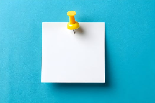 Bright yellow pushpin secures blank white paper against vibrant blue background for notes or reminders photo