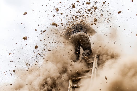 A man climbing up a ladder covered in dust photo