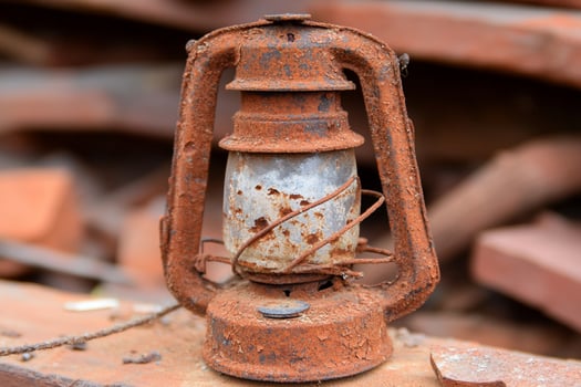 A rusty old lantern sitting on a pile of rubble photo