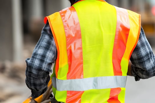 A man in a yellow vest and plaid shirt walking down the street photo