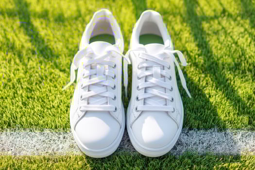 White tennis shoes standing on the baseline of a green tennis court photo