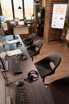 Modern office with nobody present is organized with computer systems and multiple chairs. A well arranged brick wall workplace, ready for company analysis and marketing discussions among employees. photo