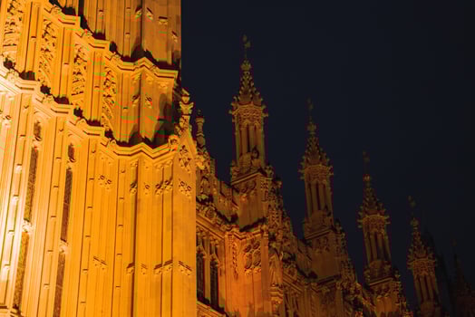 Detailed view of the Palace of Westminster in London, featuring illuminated spires and ornate carvings against a dark night sky. photo