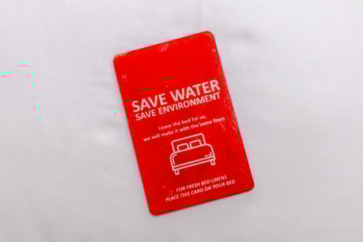 Message about save water and save the environment on a card above the hotel bed photo