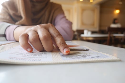 Hand pointing at menu in a cozy cafe during afternoon hours photo