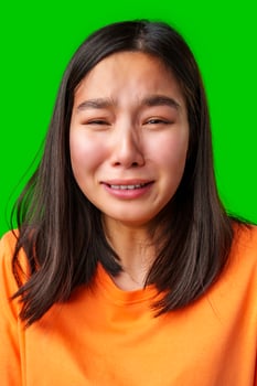 Young woman shows emotional expression in bright orange shirt against vivid green background photo