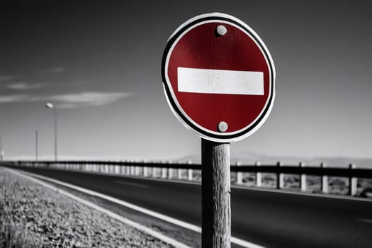 No entry sign stands guarding empty road on cloudy day photo