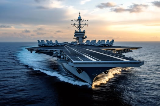 Powerful aircraft carrier cruising on the ocean at sunset with fighter jets on deck photo