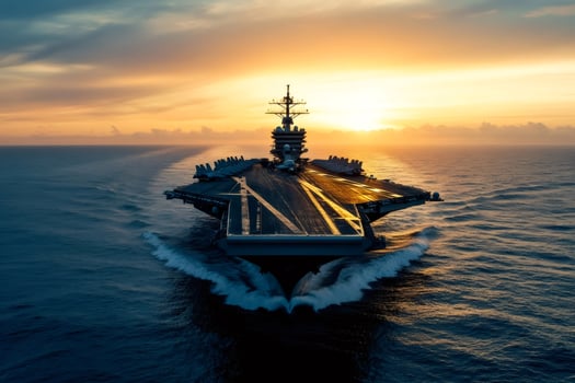 Aircraft carrier sailing on the ocean at sunset with fighter jets parked on deck photo