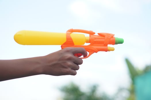 Kid hand hold plastic toy gun, squirt gun to shoot together. Concept, children play. Kid water pistol toy. Favorite equipment for Songkran Festival in Thailand. photo