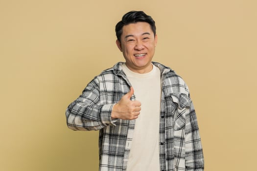 Asian man raises thumbs up agrees give positive reply recommends advertisement likes good idea photo