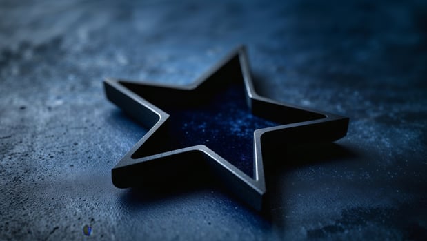 A smooth black star shape on a textured dark blue surface photo