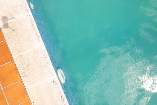 top-down view of a swimming pool with brown tile surround aerial landscape of a private swimming pool with blue water photo