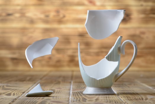 A breaking vintage porcelain cup on a wooden table photo
