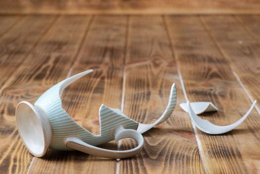 A broken coffee cup on a wooden floor photo