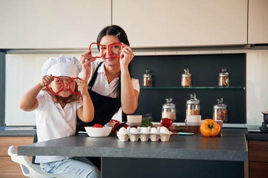 Playing with slices, of pepper. Mother ,with her daughter are preparing food on the kitchen photo