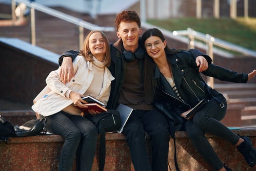 Embracing each, other. Three young ,students are outside the university outdoors photo