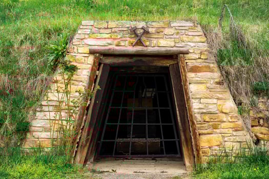 View of the entrance to an old stone mine covered with a steel grate photo