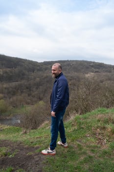 Man enjoying the serene landscape on a cloudy day near a river in the countryside photo