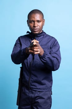 Portrait of african american security personnel mimics holding an imaginary pistol, target shooting with his hands in the shape of a gun. Male guarding agent acting serious in studio. photo
