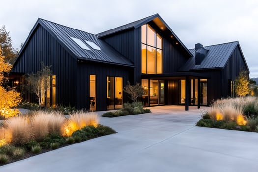 Modern black barn house featuring large windows and landscaping at sunset photo
