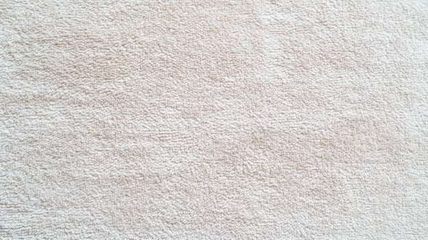 Soft beige towel fabric texture close up showing detailed loops and absorbent surface ideal for home textile and cleanliness concepts. photo