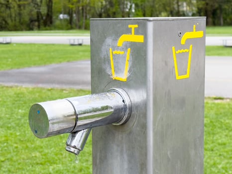 Outdoor stainless steel water fountain in park with yellow tap symbols photo