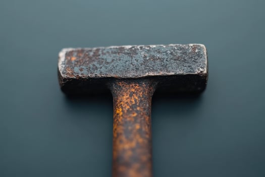 Rusty hammer resting on a dark surface highlighting tool wear and texture details photo
