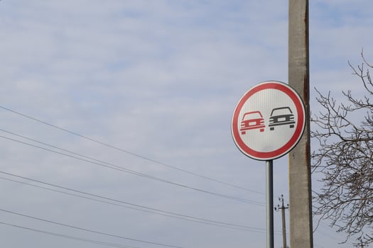 A no overtaking traffic sign is clearly visible beneath a cloudy sky, warning motorists effectively photo